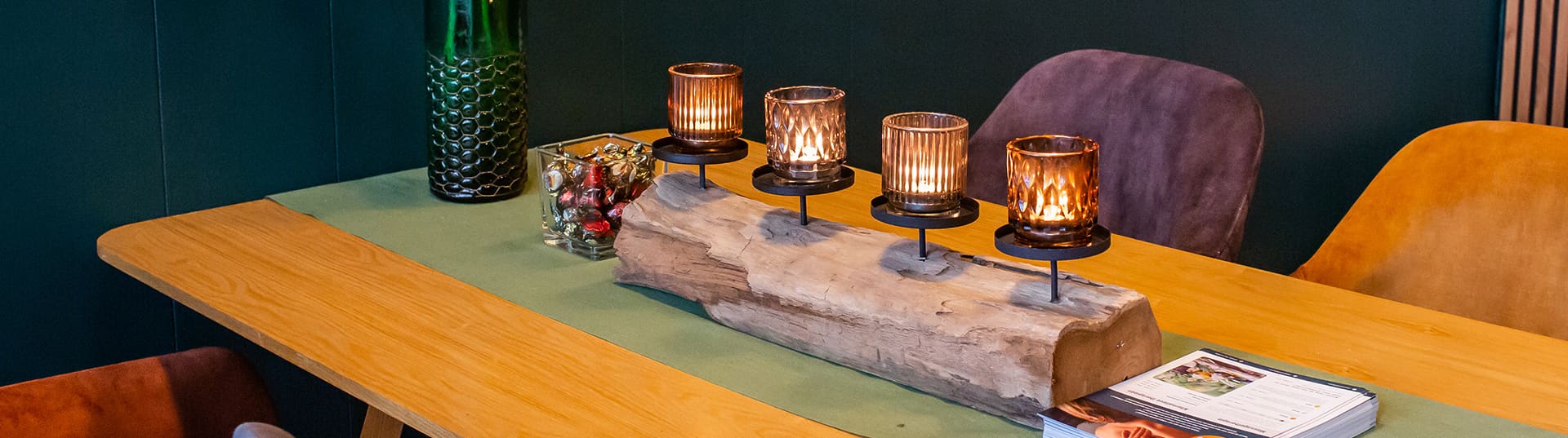 Waxinelichtjes op een drijfhouten blok op de grote tafel in de salon.