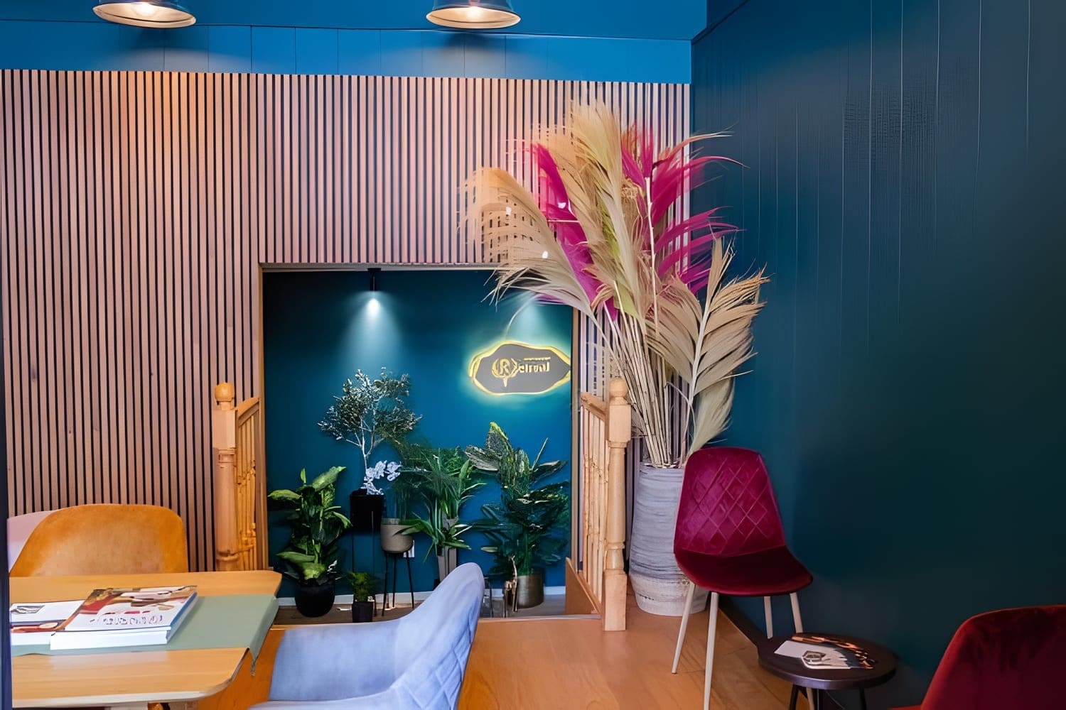 De lounge van de salon met houten lamellen, droogbloemen en een velours stoel.