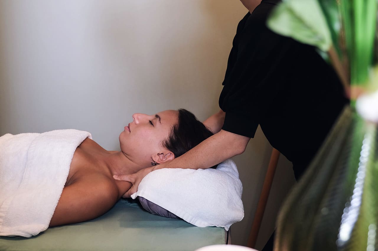 Een gast krijgt een nek- en schoudermassage op de behandeltafel bij Retreat QoQo Massage.