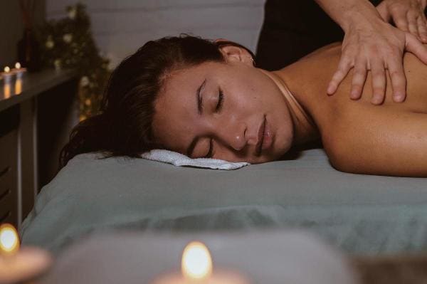 Een gast krijgt bij kaarslicht een rugmassage.