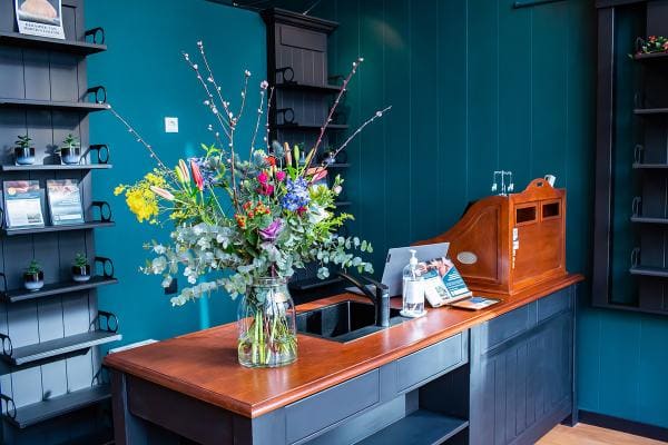 De balie met bloemen tegen een petrolblauwe wand.