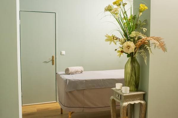 Een behandelruimte in zachtgroen met bloemen en kaarsen.