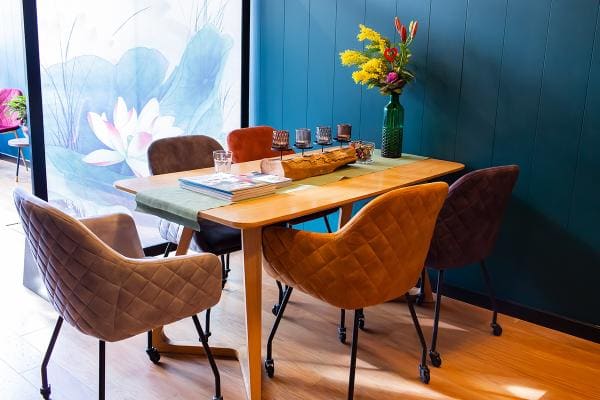 De grote tafel met velours stoelen voor de lotuswand.