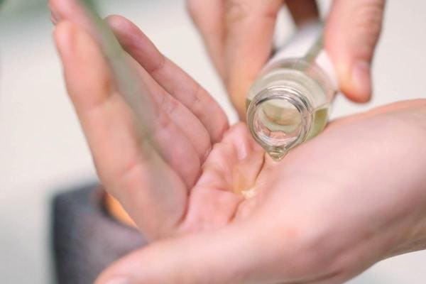 De masseur giet massageolie in de hand.