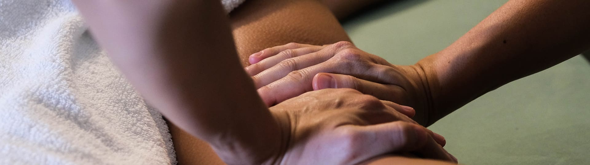 Twee handen masseren een arm op de behandeltafel.